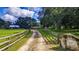 Scenic driveway leading to the property, lined with a rustic wooden fence and lush greenery on either side at 4292 Sw 73Rd Trl, Bushnell, FL 33513