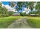 View of the log cabin, barn, and surrounding green lawn area with mature shade trees at 4292 Sw 73Rd Trl, Bushnell, FL 33513
