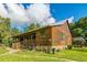 Rustic log cabin with a metal roof and a wrap-around porch, surrounded by lush greenery at 4292 Sw 73Rd Trl, Bushnell, FL 33513