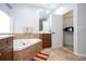 Bright bathroom with a tub, brown cabinets, mirrors, white counter tops and a door leading into the walk-in-closet at 7036 Mapperton Dr, Windermere, FL 34786
