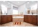 Bright bathroom featuring dual vanities with brown cabinetry, tile flooring, a soaking tub, and large mirrors at 7036 Mapperton Dr, Windermere, FL 34786