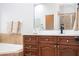 Bathroom vanity with brown wood cabinets, quartz countertop, soaking tub, framed mirror and tile backsplash at 7036 Mapperton Dr, Windermere, FL 34786
