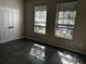 Neutral bedroom with wood floors, two windows, white trim, and a double door closet at 7036 Mapperton Dr, Windermere, FL 34786