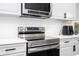 Close-up of stainless range and microwave in kitchen with wavy backsplash at 7036 Mapperton Dr, Windermere, FL 34786