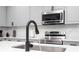 Close-up of stainless sink, microwave, and wavy backsplash in kitchen at 7036 Mapperton Dr, Windermere, FL 34786