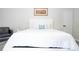 Bright main bedroom with white bedding and a white bed frame, grey wood floors, and a comfortable armchair at 7036 Mapperton Dr, Windermere, FL 34786