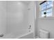 Bright bathroom featuring a tiled bathtub and shower with a toilet and a window with a green plant at 29912 Cypress Pointe, Deer Island, FL 32778