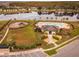 Aerial view of community pool, pool house, playground, and lake, surrounded by palm trees and landscaping at 1548 Astoria Arbor Ln, Orlando, FL 32824