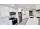 Bright kitchen featuring stainless steel appliances, white cabinetry, quartz countertops and wood floating shelves at 2469 Courtland Blvd, Deltona, FL 32738