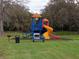 Community playground with colorful play structure, picnic table, grill, and seating area surrounded by trees and green grass at 3110 Port Royal Dr, Orlando, FL 32827