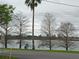 Water view showing trees lining a road near a lake with city buildings in the distance on a cloudy day at 4200 Lake Underhill Rd # A, Orlando, FL 32803