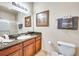 A bathroom features a shower with glass doors, a toilet, a sink and vanity with granite counters and a picture at 1301 Tuscan Ter # 9401, Davenport, FL 33896