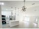 Open-concept kitchen featuring stainless steel appliances, an island, modern pendant lighting, and bright white cabinets at 3245 Se 142Nd Pl, Summerfield, FL 34491