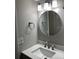 Modern bathroom with a round mirror, stainless steel fixtures and white countertop sink at 948 Lake Destiny Rd # G, Altamonte Springs, FL 32714