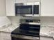 Close-up of kitchen featuring stainless steel microwave, oven and stone countertops at 948 Lake Destiny Rd # G, Altamonte Springs, FL 32714