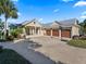 House exterior featuring a three-car garage and landscaped yard at 12943 Se Sunset Harbor Rd, Weirsdale, FL 32195
