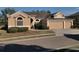 Tan house with three-car garage and lush landscaping at 510 Coventry Rd, Davenport, FL 33897