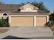 Two-car garage with tan doors and white trim at 510 Coventry Rd, Davenport, FL 33897