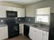 Modern kitchen with white cabinets, black appliances, and blue tile backsplash at 1316 Hackett St, Mount Dora, FL 32757