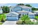 Beautiful two-story house with light blue exterior, stone accents, and a three-car garage at 1457 Olympic Club Blvd, Champions Gate, FL 33896