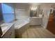 Bathroom with double vanity, corner soaking tub, and wood-look tile floors at 124 Dakota Ave, Groveland, FL 34736