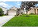Charming home featuring a well-manicured lawn, mature tree, and a two-car garage at 8007 Acadia Estates Ct, Kissimmee, FL 34747