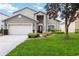 Charming home featuring a well-manicured lawn, mature tree, and a two-car garage at 8007 Acadia Estates Ct, Kissimmee, FL 34747