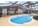Backyard features a kidney-shaped pool with a screen enclosure and patio furniture at 8007 Acadia Estates Ct, Kissimmee, FL 34747