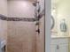 Close-up of bathroom shower featuring neutral tile, black accent stripe and mounted caddy at 12854 Sw 77Th Cir, Ocala, FL 34473