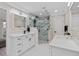 Bathroom featuring double vanities and frameless shower with white marble styled ceramic tile at 301 Rippling Ln, Winter Park, FL 32789