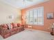 Relaxing sitting room with coral walls, comfy sofa, and large window at 461 Troy Loop, The Villages, FL 32162