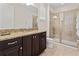 Bathroom featuring granite counters, dark cabinetry, large mirror, and glass enclosed shower at 220 Clawson Way, Kissimmee, FL 34747