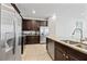 Modern kitchen with stainless steel appliances, granite counters, brown cabinets and tile flooring at 220 Clawson Way, Kissimmee, FL 34747