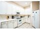 Bright kitchen featuring white cabinetry, appliances, and tile flooring, offering a clean and functional space at 301 New Providence Promenade, Davenport, FL 33897