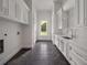 Long laundry room features black tile floors, white cabinetry, and a window view to the outdoors at 8570 Nw 31St Lane Rd, Ocala, FL 34482