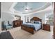 This primary bedroom features a tray ceiling, ensuite bathroom and plenty of natural light at 3303 Ridgewood Path, The Villages, FL 32163