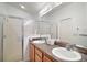 Bathroom featuring double sinks, wood cabinets, a framed mirror, and glass enclosed shower at 2378 Ridgeway Ct, The Villages, FL 32162