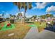 Community mini golf course featuring colorful obstacles, lush landscaping, and towering palm trees under a sunny, blue sky at 9000 Us Highway 192 # 242, Clermont, FL 34714