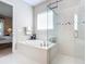 Bright bathroom featuring a soaking tub, a glass enclosed shower, and neutral tile at 584 Aldenham Ln, Ormond Beach, FL 32174