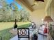 Relaxing covered patio with seating area overlooking a beautifully landscaped backyard and trees at 584 Aldenham Ln, Ormond Beach, FL 32174