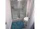 Bathroom featuring a sliding glass shower door, toilet, and blue rug on gray flooring at 3575 Cochran St, The Villages, FL 32163