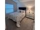 Well-lit bedroom features a plush bed with decorative pillows and glass shelving against neutral walls at 3575 Cochran St, The Villages, FL 32163