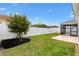 A well-maintained backyard with green lawn, white fence, a young tree, and screened in patio at 3381 Harris Ct, The Villages, FL 32163