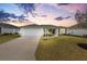 Charming single-story home with well-manicured lawn and inviting curb appeal at sunset at 3381 Harris Ct, The Villages, FL 32163