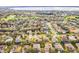 Beautiful aerial view of homes in a peaceful, suburban neighborhood with mature trees, a golf course, and a distant lake at 1086 Harmony Ln, Clermont, FL 34711