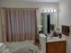 Bathroom featuring a shower-tub combo with a curtain and a wooden vanity at 30126 Sandbunker Ln, Sorrento, FL 32776