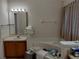 Bathroom featuring a vanity sink, large mirror with lights, and a bathtub with striped shower curtains at 30126 Sandbunker Ln, Sorrento, FL 32776