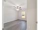 Bedroom features gray wood flooring, ceiling fan, and a window overlooking the lush backyard at 20184 Sw 57 St, Dunnellon, FL 34431