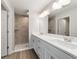 Bathroom with double sink vanity, large mirror, and a walk-in shower with tile surround and fixtures at 20184 Sw 57 St, Dunnellon, FL 34431