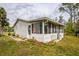 Rear exterior view showcases an enclosed porch, siding, and a spacious yard, perfect for upgrades at 2486 Daytona Park Rd, Deland, FL 32724